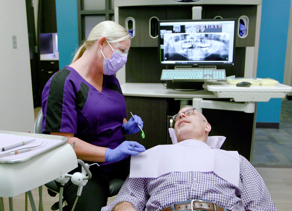 hygenist talking with patient reclining in dental chair